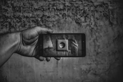 Cropped hand photographing outlet on wall