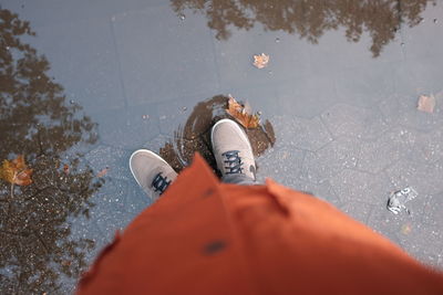 Low section of man standing in puddle on footpath