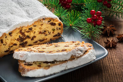 Christmas stollen on a plate with a rustic background and fir branch. 