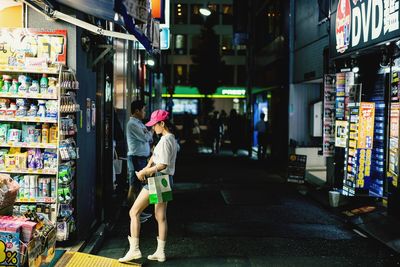 Rear view of woman walking in illuminated store at night