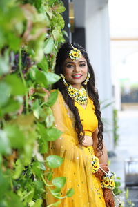 Portrait of woman in yellow dress standing by plants