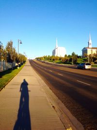 Shadow of man on road against clear sky