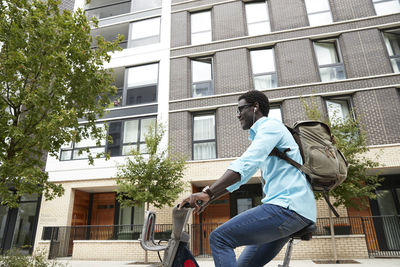 Smiling man listening music while commuting on bicycle in city