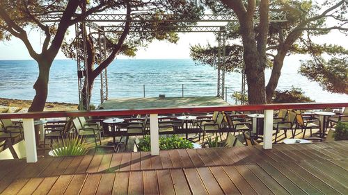 Chairs and table by sea against sky