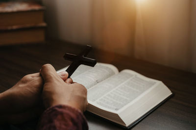 Cropped hand of woman holding book on table