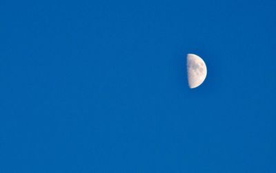 Low angle view of moon against clear blue sky