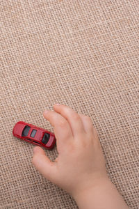 Close-up of hand holding toy car on jute