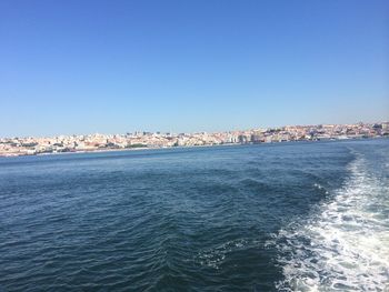View of city at waterfront against blue sky