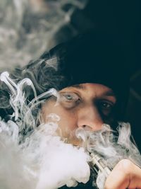 Man smoking electronic cigarette against black background