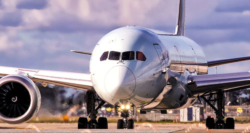 Airplane on airport runway against sky