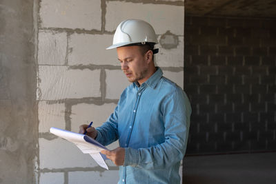 Side view of man standing against wall