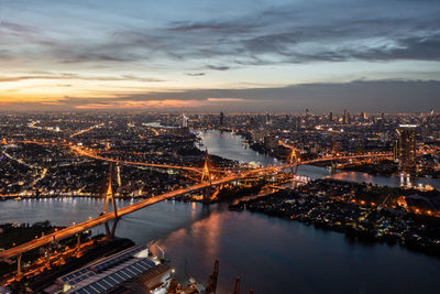 Illuminated bridge over river against sky at sunset
