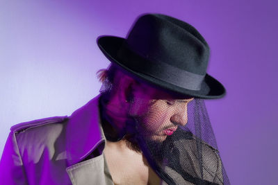 Close-up portrait of woman wearing hat against gray background