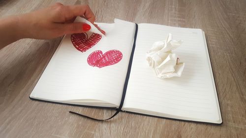 Cropped image of hand holding book on table