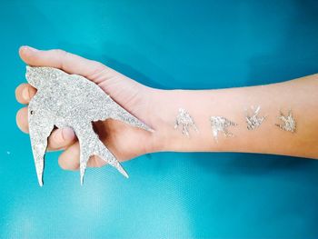 Cropped image of woman holding artificial bird decoration with shiny tattoo on hand