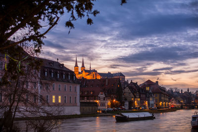 City at waterfront against cloudy sky