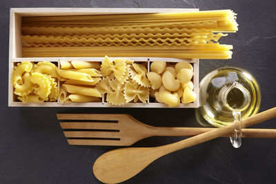 Various pasta in box with utensils on slate