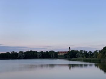 Scenic view of lake by building against sky during sunset