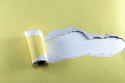 Close-up of broken paper against yellow background
