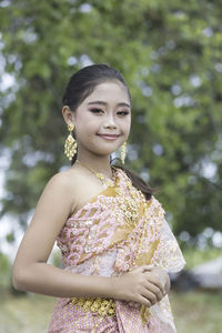 Young woman looking away while standing against trees