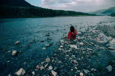 View of woman sitting on lakeshore