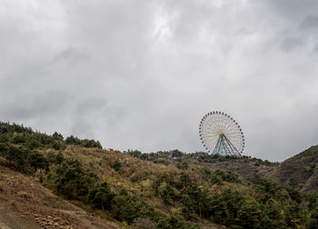 View of ferris wheel against cloudy sky