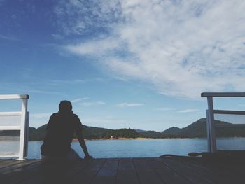 Rear view of man looking at sea against sky