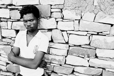 Portrait of young man standing against brick wall