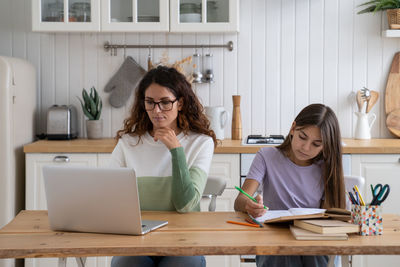 Female friends using laptop at office