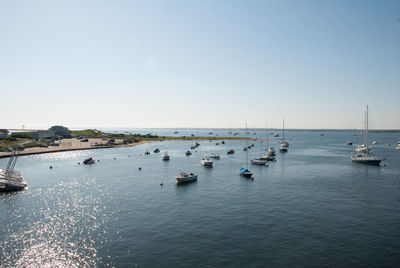 Sailboats moored on sea against clear sky