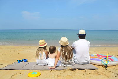 Rear view of family sitting at beach