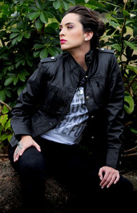 Young woman looking away while sitting on plant