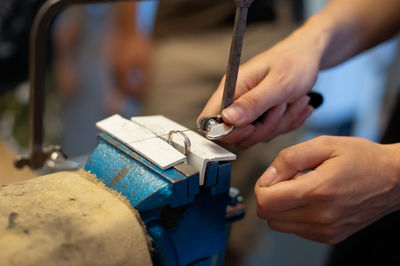 Midsection of person making wedding ring in workshop