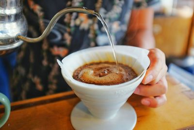 Midsection of person making drip coffee