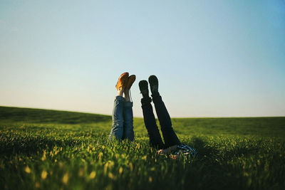 Couple with feet up amidst plants against clear sky