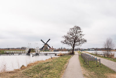 Traditional windmill by canal against sky