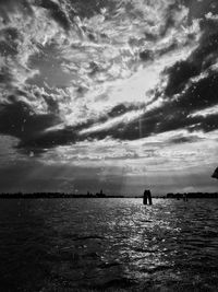 Silhouette people on sea against sky