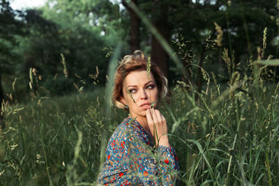 Young woman sitting on field looking away 