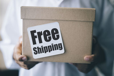 Cropped hands of boy holding cardboard box