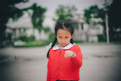 Portrait of cute girl pointing while standing on road