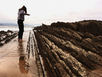 Rear view of man walking on dirt road against sky