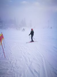 Full length of boy skiing on snow field during foggy weather