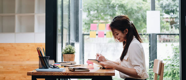 Side view of young woman using laptop at office