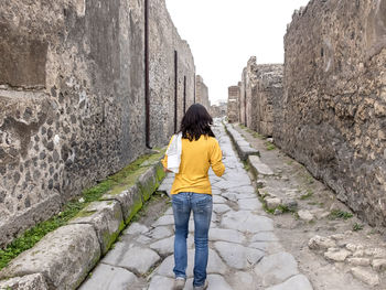 Rear view of woman standing amidst ancient built structure