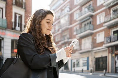 Young woman using mobile phone in city