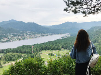 Rear view of woman looking at mountains against sky