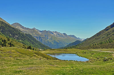 Scenic view of lake and mountains against blue sky