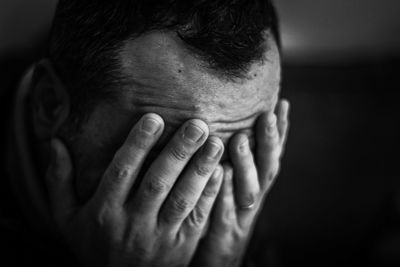 Close-up sad man covering face with hands