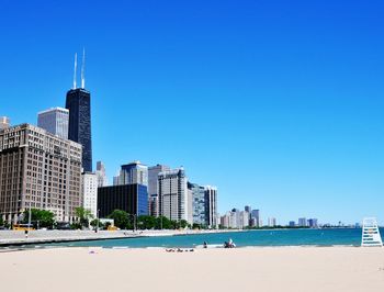 City at waterfront against blue sky