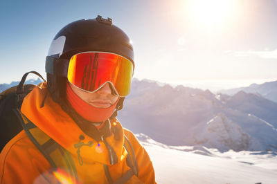 Young man in ski goggles and a helmet on a sunny snowy ski slope. portrait of a confident sportsman